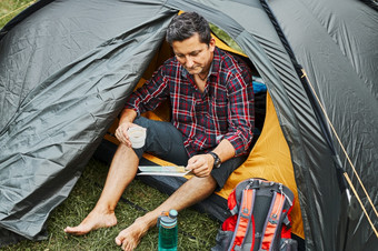 男人。看地图而规划下一个旅行男人。放松帐篷野营在夏天假期积极支出假期在户外关闭自然概念营生活