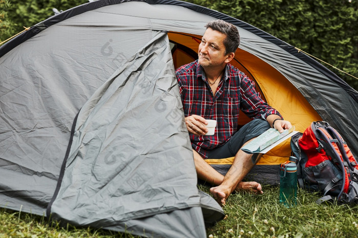 男人。放松帐篷野营在夏天假期男人。持有地图而规划下一个旅行积极支出假期在户外关闭自然概念营生活
