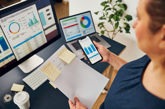 女商人工作与金融数据图表和表智能手机和电脑女人企业家看出售统计数据站桌子上办公室