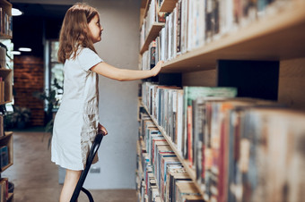 女学生看书前书架上学校图书馆聪明的女孩选择文学为阅读书货架上书店学习从书学校教育好处日常阅读孩子好奇心回来学校