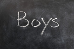 男孩词写与白色粉笔黑板上
