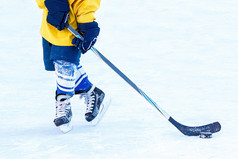 脚年轻的曲棍球球员曲棍球坚持和顽皮的小妖精特写镜头的背景的冰