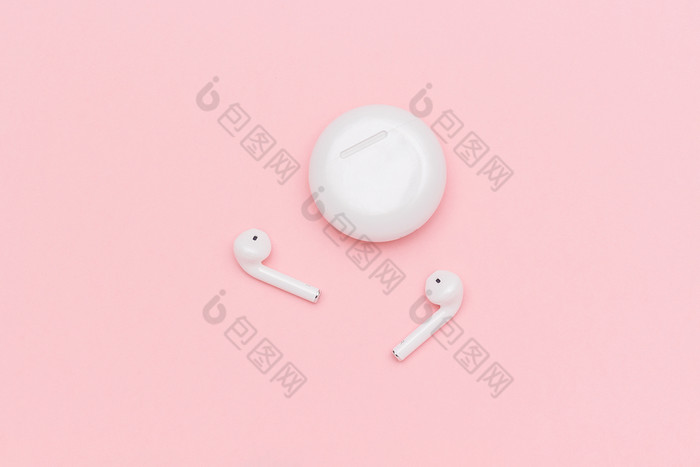 白色无线蓝牙耳机和充电情况下粉红色的纸背景模板为文本你的设计平躺前视图复制空间白色无线蓝牙耳机和充电情况下粉红色的纸背景模板为文本你的设计平躺前视图复制空间
