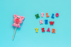 有趣的粉红色的猪棒棒糖和多色登记你好新一年蓝色的背景前视图布局概念问候卡一年的猪猪棒棒糖和文本你好新一年