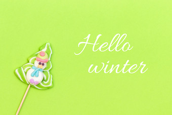 文本你好冬天和糖果棒棒糖有趣的雪人圣诞节树绿色背景前视图问候卡文本你好冬天和糖果棒棒糖有趣的雪人