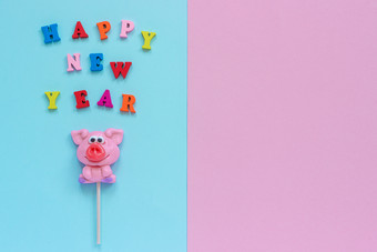 有趣的粉红色的猪棒棒糖和多色登记快乐新一年粉红色的蓝色的背景前视图复制空间布局概念问候卡一年的猪猪棒棒糖和文本快乐新一年