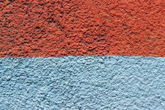 片段混凝土墙画与橙色和蓝色的油漆一半背景纹理