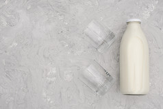 牛奶玻璃瓶和两个空眼镜灰色的背景与复制空间平躺前视图牛奶玻璃瓶和两个空眼镜灰色的背景与复制空间平躺前视图