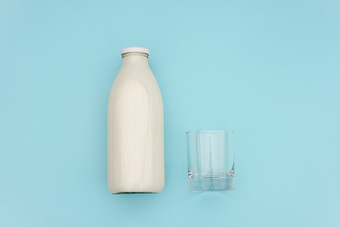 牛奶玻璃瓶和空玻璃蓝色的背景与复制空间平躺前视图牛奶玻璃瓶和空玻璃蓝色的背景与复制空间平躺前视图