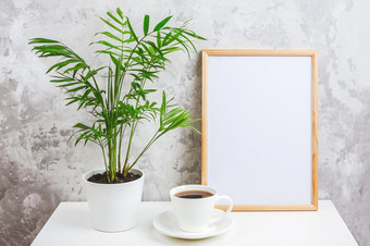 木垂直框架与白色空白卡杯咖啡和绿色异国情调的棕榈花能表格灰色的混凝土墙背景模型模板为你的设计文本木垂直框架与白色空白卡杯咖啡和绿色异国情调的棕榈花能表格灰色的混凝土墙背景模型模板为你的设计文本
