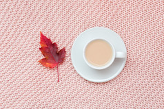 杯咖啡与牛奶和红色的秋天叶柔和的粉红色的针织格子背景秋天舒适的概念平躺前视图复制空间杯咖啡与牛奶和红色的秋天叶柔和的粉红色的针织格子背景秋天舒适的概念平躺前视图复制空间