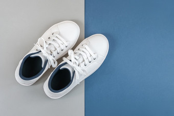 白色体育鞋子运动鞋与鞋带灰色蓝色的背景体育运动生活方式概念前视图平躺复制空间白色体育鞋子运动鞋与鞋带灰色蓝色的背景体育运动生活方式概念前视图平躺复制空间