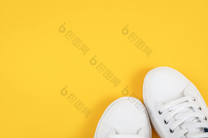 白色体育鞋子运动鞋与鞋带黄色的背景体育运动生活方式概念前视图平躺复制空间白色体育鞋子运动鞋与鞋带黄色的背景体育运动生活方式概念前视图平躺复制空间