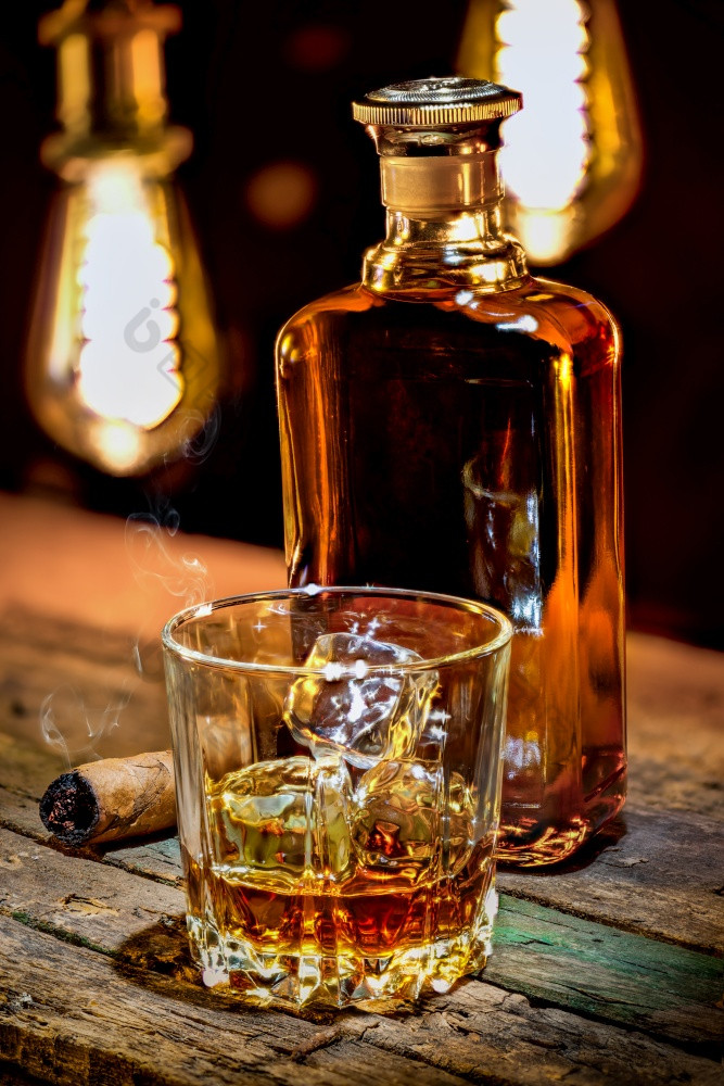 威士忌瓶和玻璃与雪茄木表格玻璃威士忌和雪茄