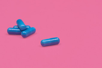 医疗背景蓝色的胶囊药丸粉红色的背景蓝色的胶囊药丸传播樱红色粉红色的背景与复制空间宏照片医疗背景与药片