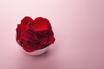 美丽的红色的玫瑰花瓣白色碗温柔的粉红色的背景玫瑰花瓣使用为香水化妆品和洗澡红色的彩色的有机草本植物宏照片关闭从以上美丽的红色的玫瑰花瓣白色碗温柔的粉红色的背景玫瑰花瓣使用为香水化妆品和洗澡