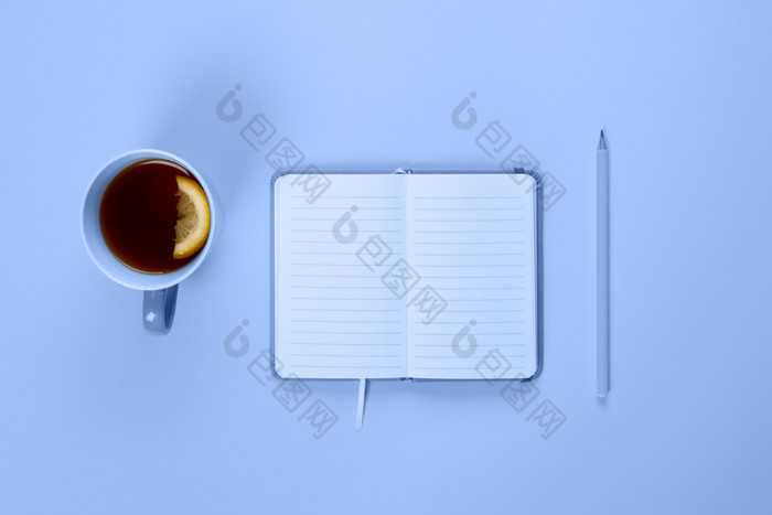 茶杯和花俏的笔记本与空空白页面蓝色的桌子上从以上规划和设计概念前视图平躺复制空间模拟茶杯和花俏的笔记本与空空白页面蓝色的桌子上从以上规划和设计概念
