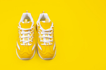 新黄色的女运动鞋黄色的背景单色流行艺术概念前视图黄色的女运动鞋黄色的背景