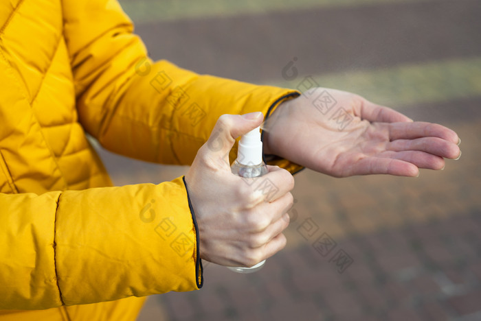 年轻的女人消毒手与手洗手液的街关闭冠状病毒传播预防措施措施概念年轻的女人消毒手与手洗手液的街