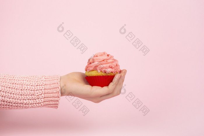 美味的蛋糕女手光粉红色的背景单色节日概念与蛋糕和粉红色的结霜复制空间单色节日概念与蛋糕和粉红色的结霜复制空间