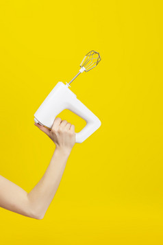 白色厨房混合机女手孤立的明亮的黄色的背景现代厨房概念白色厨房混合机女手孤立的明亮的黄色的背景