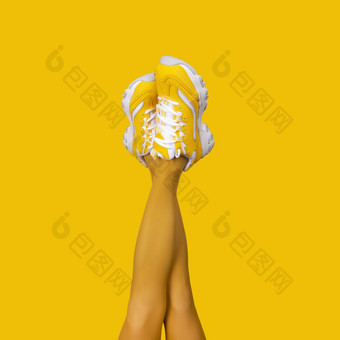 新黄色的女运动鞋长纤细的女人腿黄色的连裤袜孤立的黄色的背景单色流行艺术概念广场作文新黄色的女运动鞋长纤细的女人腿黄色的连裤袜孤立的黄色的背景
