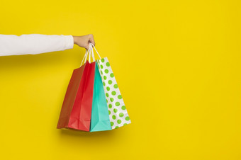 购物出售概念女手持有购物纸袋孤立的黄色的背景横幅与复制空间女手持有购物纸袋孤立的黄色的背景