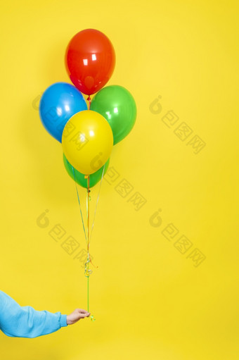 女手持有群色彩斑斓的气球聚会，派对现在概念绿色红色的黄色的和蓝色的气球和手孤立的黄色的使用女手持有群色彩斑斓的气球聚会，派对现在概念绿色红色的黄色的和蓝色的气球和手孤立的黄色的使用