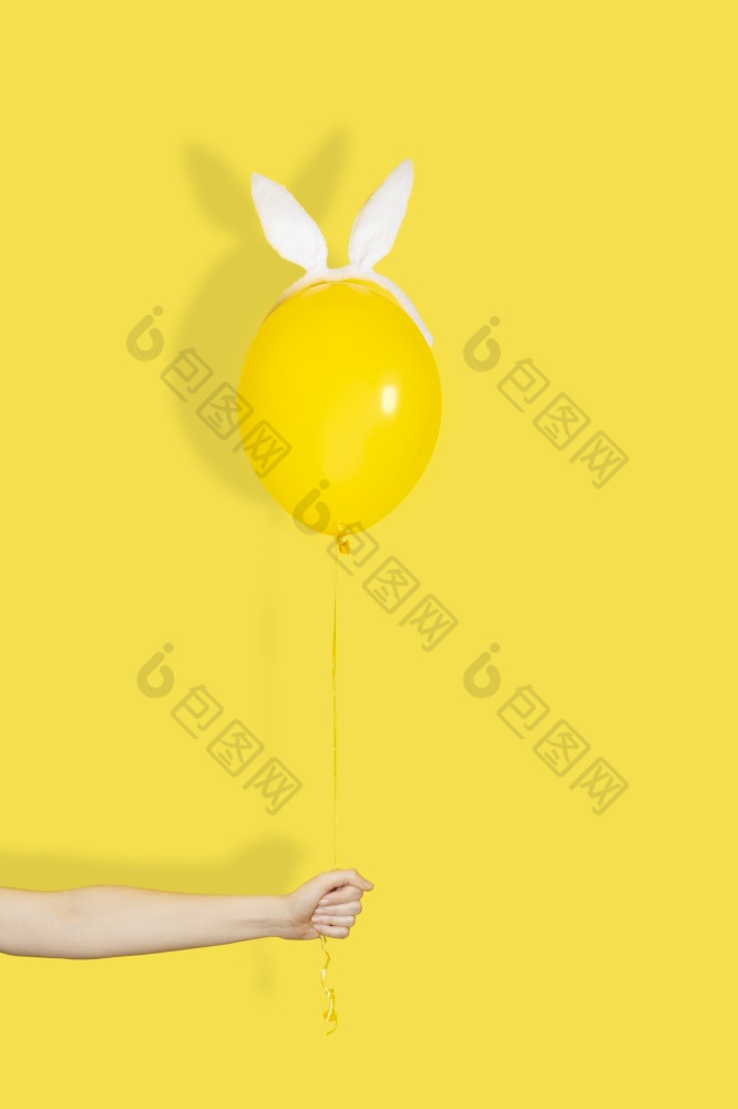 有创意的复活节最小的概念手持有黄色的气球兔子耳朵单色有创意的复活节最小的概念手持有黄色的气球兔子耳朵单色