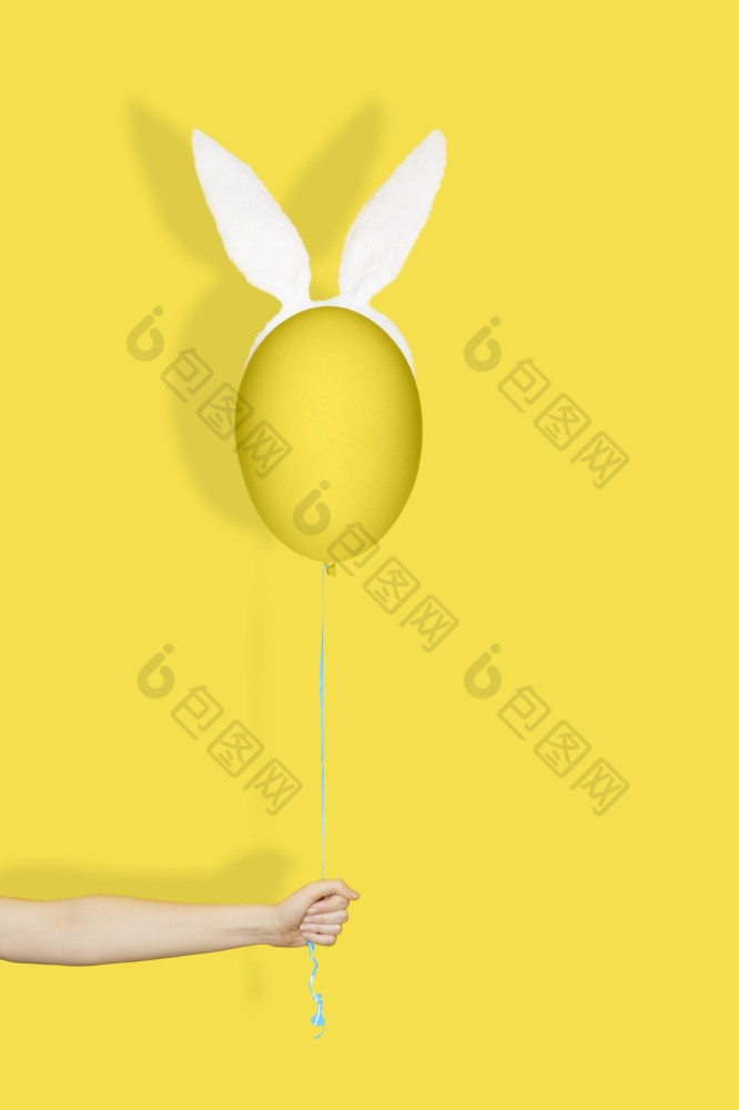 有创意的复活节最小的概念手持有黄色的蛋兔子耳朵就像气球字符串单色复活节有创意的复活节最小的概念手持有黄色的蛋兔子耳朵就像气球字符串单色复活节