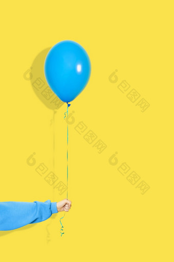 女手持有蓝色的<strong>气球</strong>聚会，派对现在概念蓝色的<strong>气球</strong>和手蓝色的连帽衫孤立的黄色的使用女手持有蓝色的<strong>气球</strong>聚会，派对现在概念蓝色的<strong>气球</strong>和手蓝色的连帽衫孤立的黄色的使用