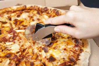 关闭手切割披萨与披萨刀美味的paperoni披萨开放盒子孤立的黑色的背景前视图paperoni披萨概念为意大利食物街食物快食物快速咬关闭手切割披萨与披萨刀美味的paperoni披萨开放盒子孤立的黑色的