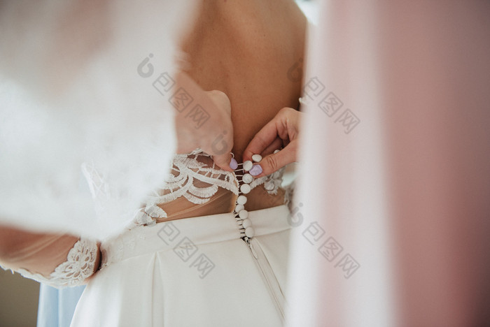白色婚礼衣服针织的新娘新娘被帮助穿的婚礼衣服的新娘rsquo准备为的婚礼新娘白色花边婚礼衣服新娘帮助把的婚礼衣服