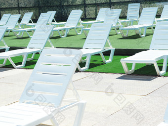 白色塑料太阳懒人的娱乐区域的池绿色地板上覆盖的形式草