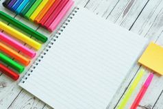 开放笔记本色彩斑斓的明亮的标记笔和粘土木背景