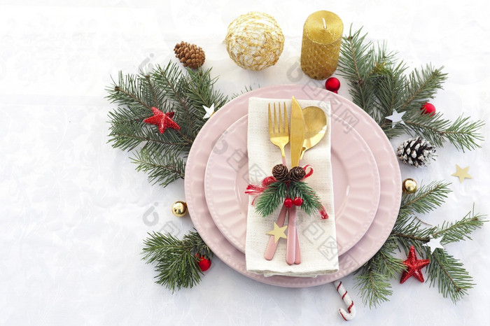 概念圣诞节表格设置两个粉红色的盘子和粉红色的和黄金餐具与装饰亚麻餐巾冷杉分支机构视锥细胞球和星星