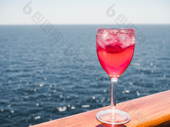 美丽的葡萄酒杯与粉红色的鸡尾酒和冰多维数据集站的开放甲板对的背景海波一边视图特写镜头概念休闲和旅行葡萄酒杯与粉红色的鸡尾酒和冰多维数据集