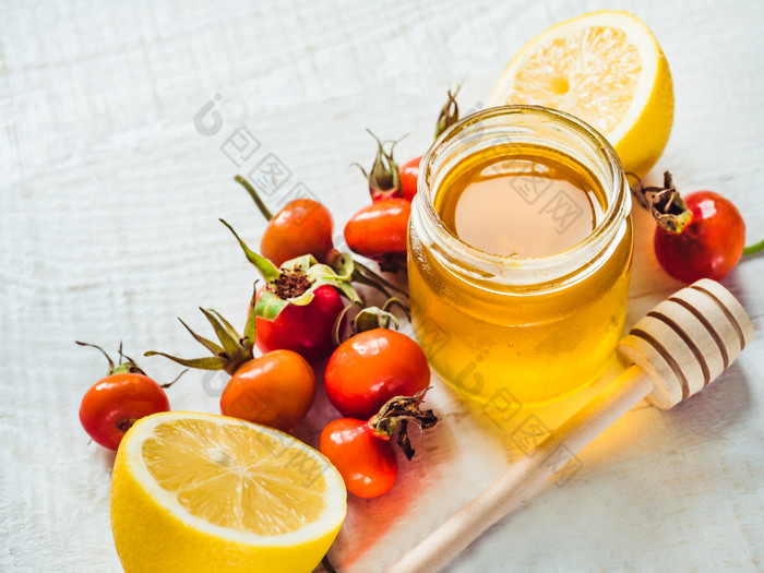 新鲜的黄色的柠檬壶蜂蜜和红色的浆果白色木表格前视图特写镜头孤立的概念防止感冒新鲜的黄色的柠檬壶蜂蜜和红色的浆果