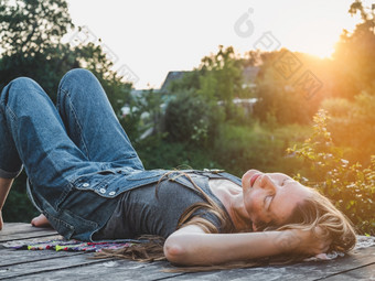 漂亮的女人说谎木阳台日落背景特写镜头一边视图户外概念休息和放松漂亮的女人说谎木阳台