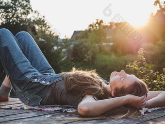 漂亮的女人说谎木<strong>阳台</strong>日落背景特写镜头一边视图户外概念休息和放松漂亮的女人说谎木<strong>阳台</strong>