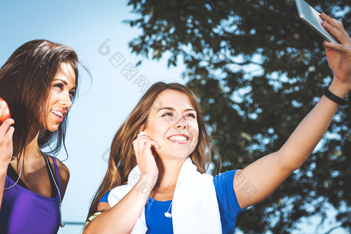 千禧一代生活方式概念两个体育女孩取自拍和微笑而培训在户外阳光明媚的一天古董效果