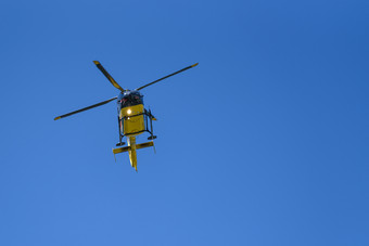通用的黄色的<strong>直升机</strong>使用为<strong>消防</strong>和救援操作的蓝色的天空背景低天使视图