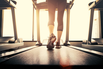 较低的身体腿部分健身女孩运行运行机跑步机健身健身房与太阳雷温暖的语气健康的和锻炼活动概念锻炼和强度培训主题