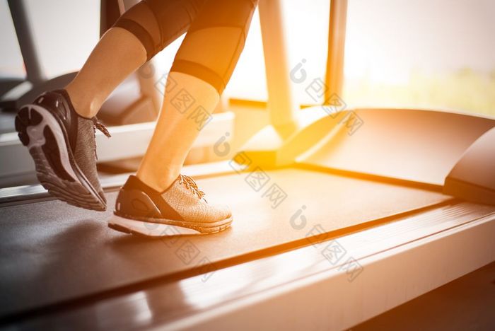 较低的身体腿部分健身女孩运行运行机跑步机健身健身房与太阳雷温暖的语气健康的和锻炼活动概念锻炼和强度培训主题