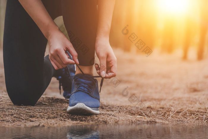 年轻的健身运行女人系鞋带在户外森林背景体育运动和自然概念农村锻炼和和运动员活动概念健康的和生活方式主题