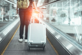 回来视图美女人旅行和持有手提箱自动扶梯机场人和生活方式概念旅行周围的世界主题冒险和业务旅行关闭较低的身体腿