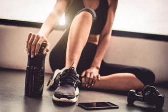 关闭女人锻炼锻炼室内健身健身房打破放松后体育运动培训与哑铃聪明的电话和蛋白质<strong>摇</strong>瓶健康的生活方式运动员和健美运动员肌肉概念
