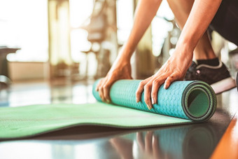 关闭运动女人折叠瑜伽床垫体育运动健身健身房培训中心背景锻炼席滚动保持后瑜伽类锻炼和体育运动培训概念手地毯