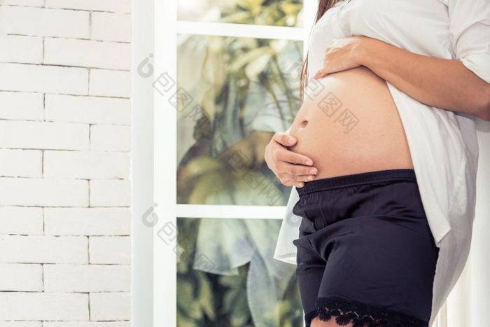 关闭肚子怀孕了女人首页室内和窗口背景健康的和孕妇父概念妈妈。取哪她的孩子肚子快乐生活妈妈之前孕妇