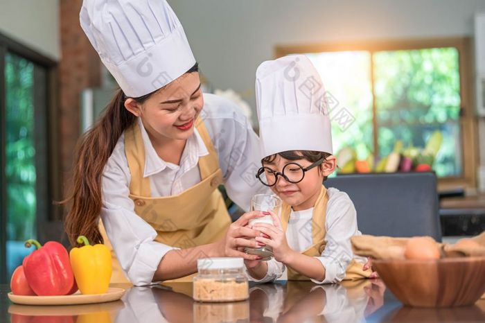 美丽的亚洲女人教学可爱的小男孩与眼镜喝牛奶厨房首页在一起生活方式和家庭儿子不喜欢牛奶和做有趣的脸与牛奶玻璃食物和喝